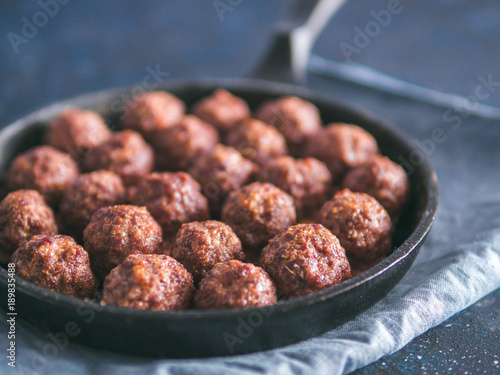 Homemade roasted beef meatballs in cast-iron skillet on dark blue background. Copy space for text. Shallow DOF photo