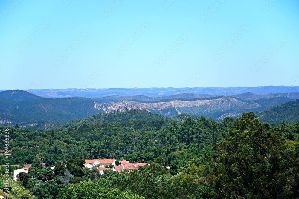 Elevated view of the mountains and countryside in the Monchique mountains with a small village in the foreground, Algarve, Portugal.
