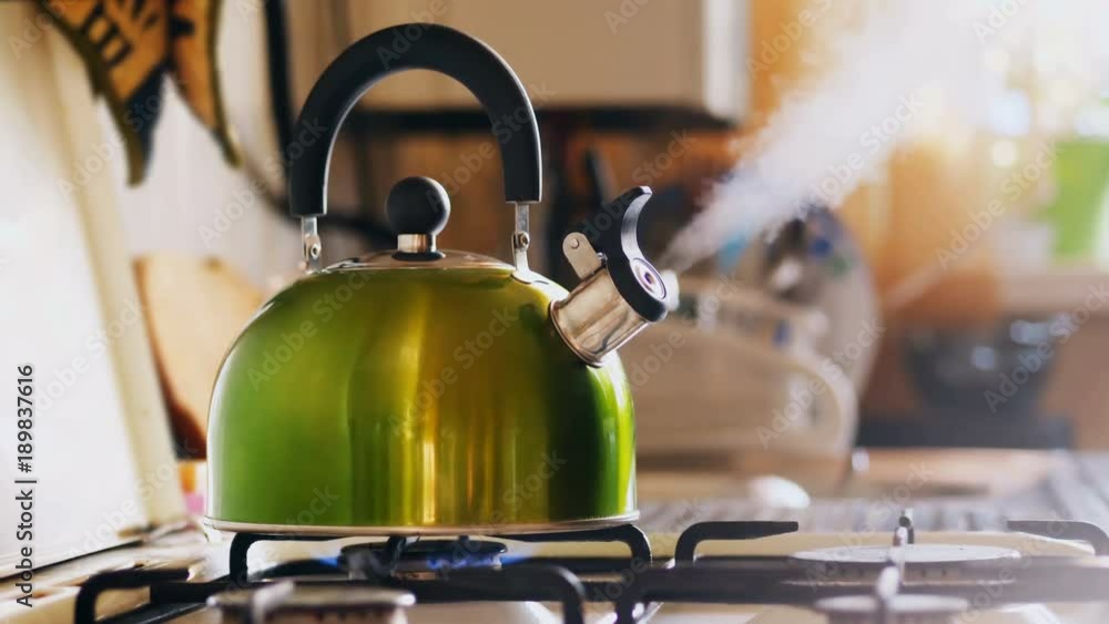 Kettle boiling on a gas stove. Boiling green kettle boiling with steam