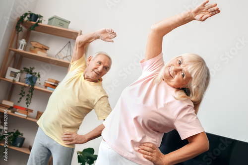 Senior couple exercise together at home health care gymnastic stretching