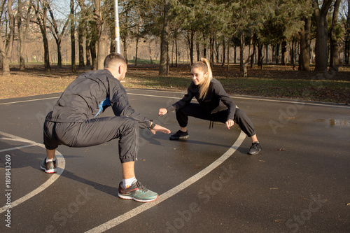 couple of young athlets do exercises outdoors in autumn park 