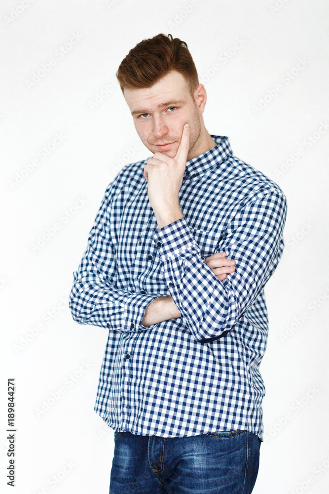 Cheerful handsome redhead young guy in black cardigan checkered shirt photographed against white wall in the studio Cheerful handsome redhead young guy in black cardigan checkered shirt photographed against white wall in the studio