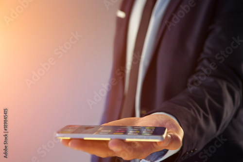 Businessman giving an empty hand with smartphone on a color background