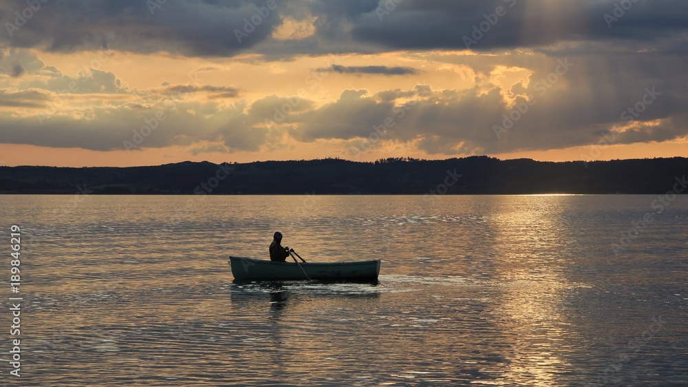 Summer sunset in Ebeltoft, Denmark. Man rowing in a small boat.