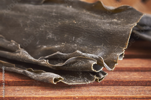 Closeup of dried kombu seaweed (Laminariaceae longissima) on wooden background photo