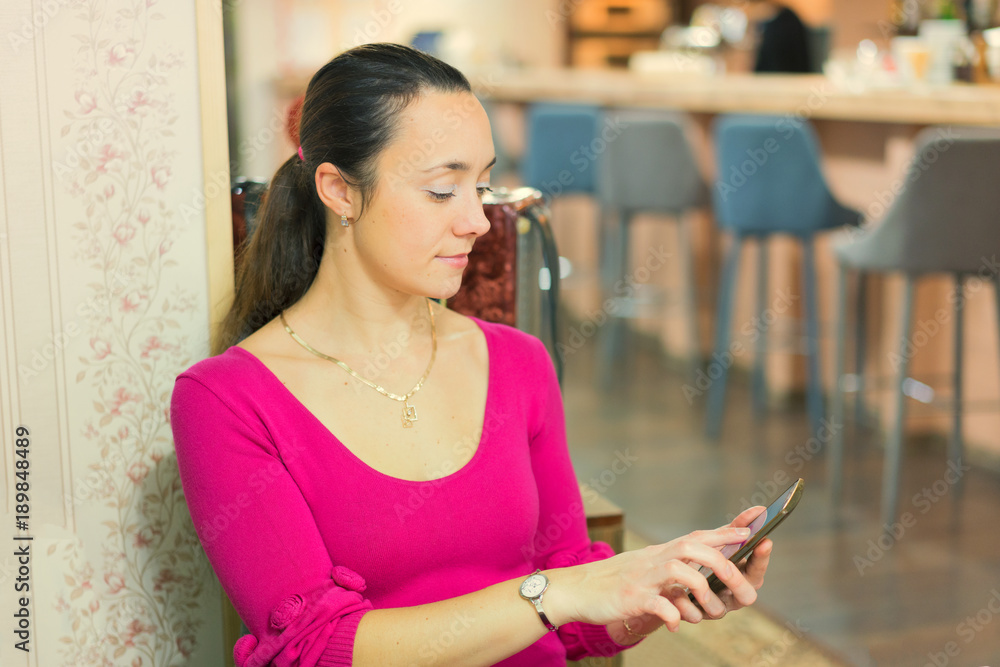 beautiful young woman in a red dress sitting in a cafe using her smartphone beautiful young woman in a red dress sitting in a cafe using her smartphone