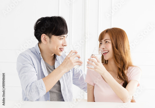 Young couple drinking clean water at home.