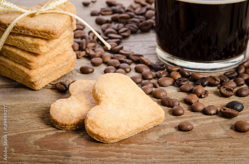 The cup of coffee, coffee beans and cookies-hearts related together on wooden table The cup of coffee, coffee beans and cookies-hearts related together on wooden table