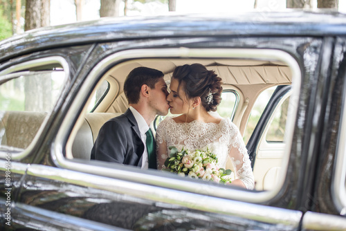 wedding couple kissing and hugging in old vintage retro car