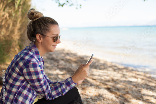 Young woman using phone on beach