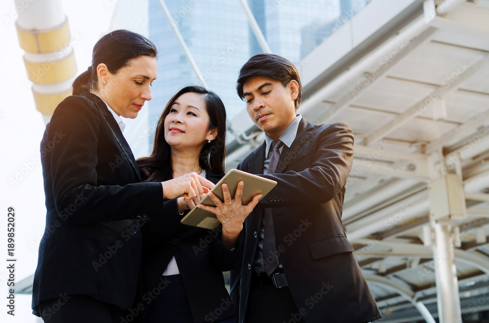 group of business people in suit talking and reading information about finance news in mobile tablet together standing in modern city, network technology, internet, successful, teamwork concept group of business people in suit talking and reading information about finance news in mobile tablet together standing in modern city, network technology, internet, successful, teamwork concept