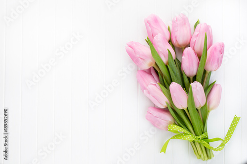 Fresh red tulip flowers bouquet on shelf in front of wooden wall.