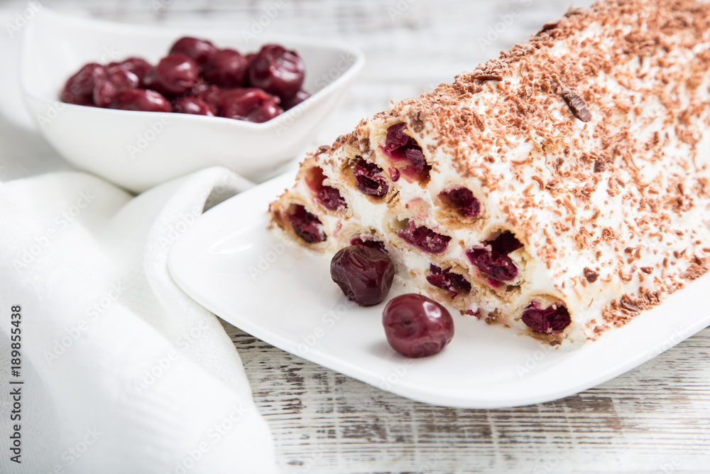 cake with cherries, cream and chocolate on a light wooden background cake with cherries, cream and chocolate on a light wooden background
