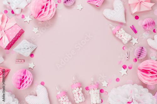 Frame made of Pink and white Paper Decorations, candy, hearts, gifts, confetti for Baby party. Flat lay, top view