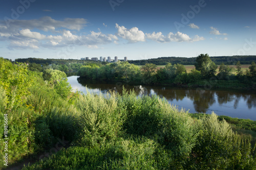 summer landscape. High grass and river under the blue sky