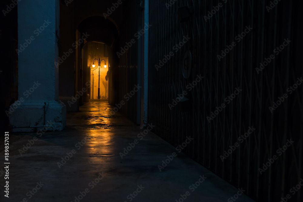 Empty dark street at night with light of latern shining through arches, Georgetown, Penang, Malaysia Empty dark street at night with light of latern shining through arches, Georgetown, Penang, Malaysia