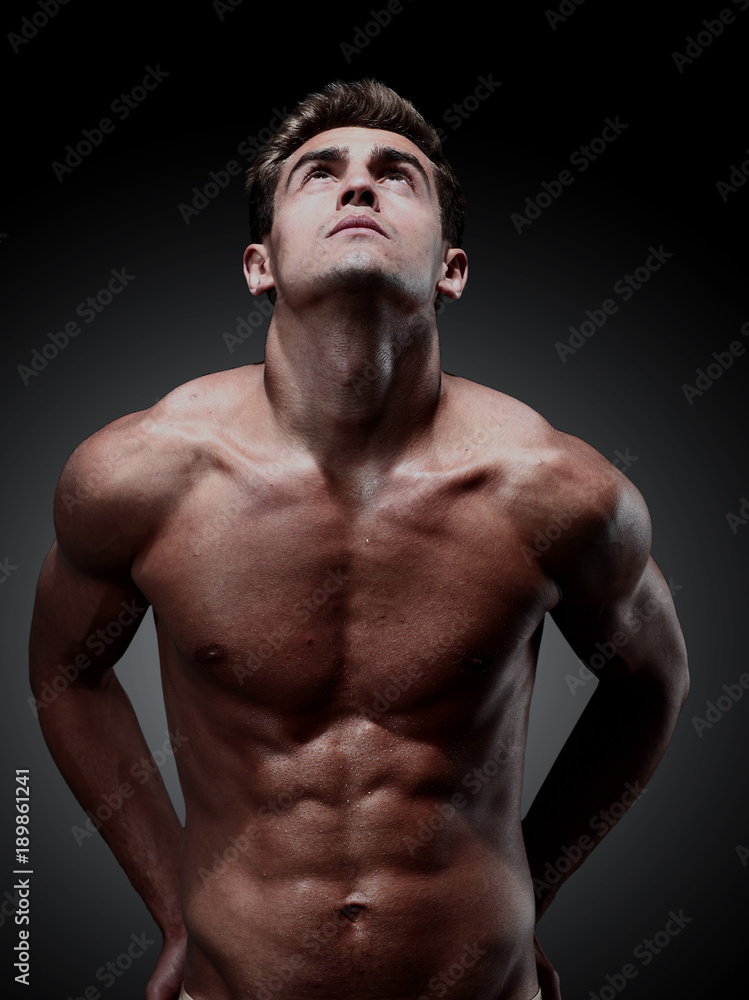 portrait of young strong man against black background portrait of young strong man against black background