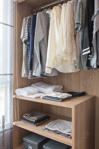 wooden closet with clothes hanging on rail