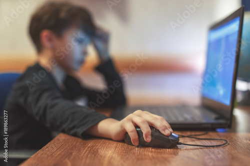 Photography Little addicted boy playing video game on laptop