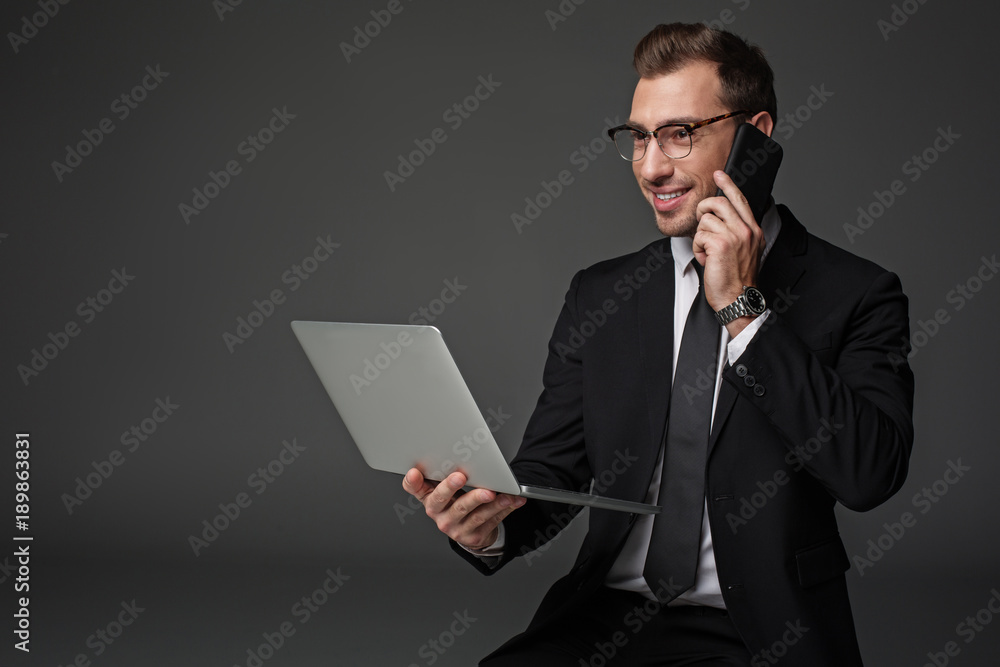 Portrait of happy male telling by mobile while working at laptop. Profession concept Portrait of happy male telling by mobile while working at laptop. Profession concept