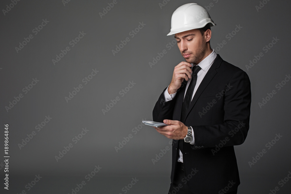 How can I spend it. Portrait of pensive builder looking at money. Profit concept. Copy space and isolated How can I spend it. Portrait of pensive builder looking at money. Profit concept. Copy space and isolated
