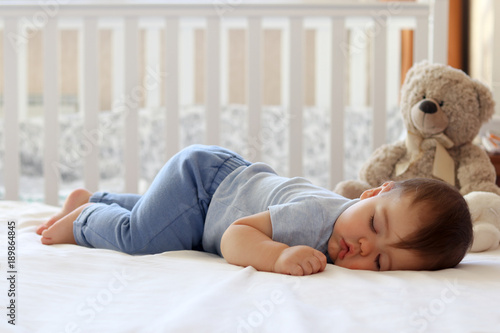 Funny baby sleeping on his stomach on bed at home. Child daytime bottom up sleeping position