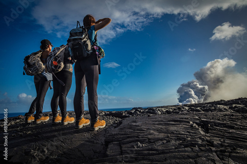 A group of three girls wearing trekking shoes standing on black lava field