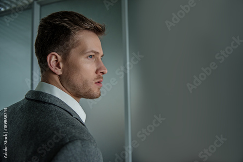 Formidable look. Profile of serious young solid businessman is standing and looking aside confidently. Copy space in the right side