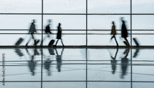 Defocused airport hall with walking travelers. They are going toward to each other in terminal lounge with luggage. Travel concept. Full length