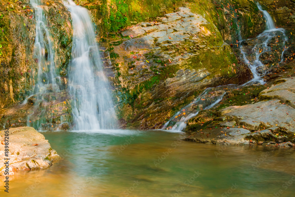 Obraz premium The cascade waterfall of the mountain river Bezumenka closeup in sunny autumn day, Sochi, Russia 