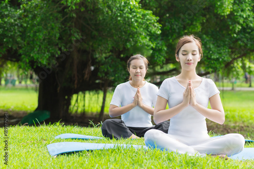 Two  Asian woman practicing yoga  at the Green park ,  Healthy lifestyle Concept.