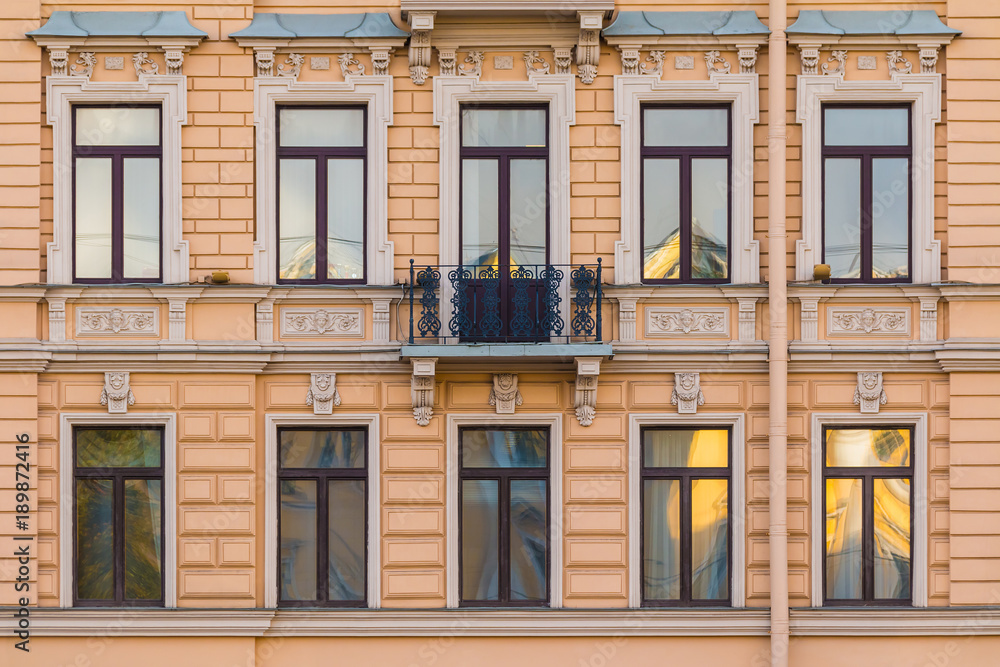 Several windows in a row and balcony on the facade of the urban historic building front view, Saint Petersburg, Russia

