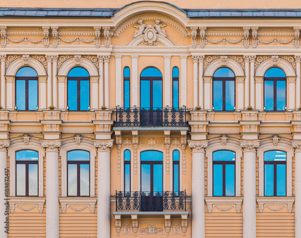 Several windows in a row and balconies on the facade of the urban historic building front view, Saint Petersburg, Russia
