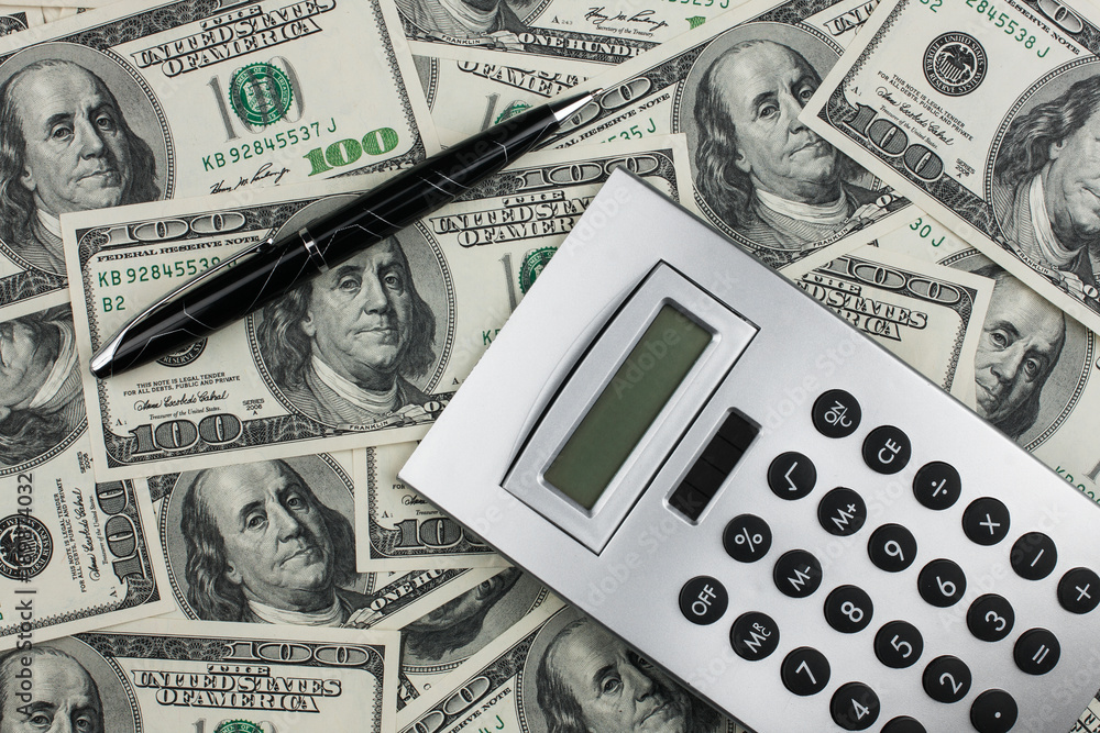 Business background. Calculator and pen lying on the background of money. Business background. Calculator and pen lying on the background of money.