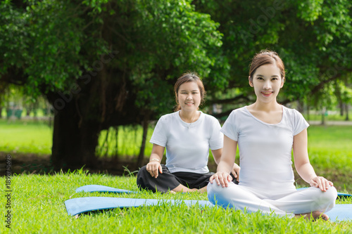 Two Asian woman practicing yoga at the Green park , Healthy lifestyle Concept.