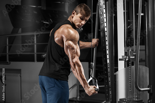 Bild auf Leinwand Muscular man working out in gym doing exercises at triceps, strong male