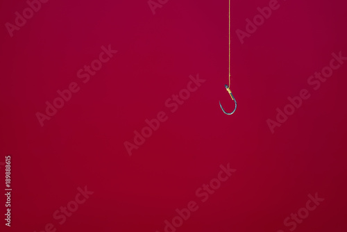 Hook hanging with yellow rope alone. On a bright red background