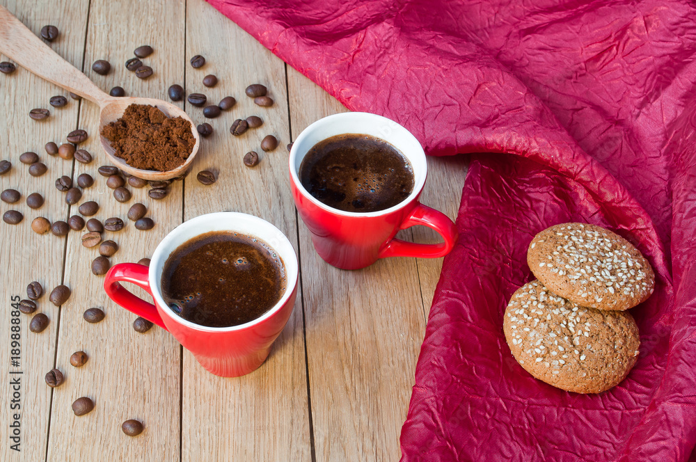 Two red cups of coffee with oatmeal cookies on a wooden table Two red cups of coffee with oatmeal cookies on a wooden table