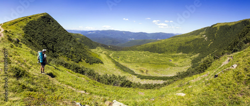 Lonely man hiker standing on a wide hill enjyoing mountain view