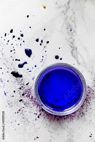 Overhead view of tin with water painted violet. Artist workplace concept.