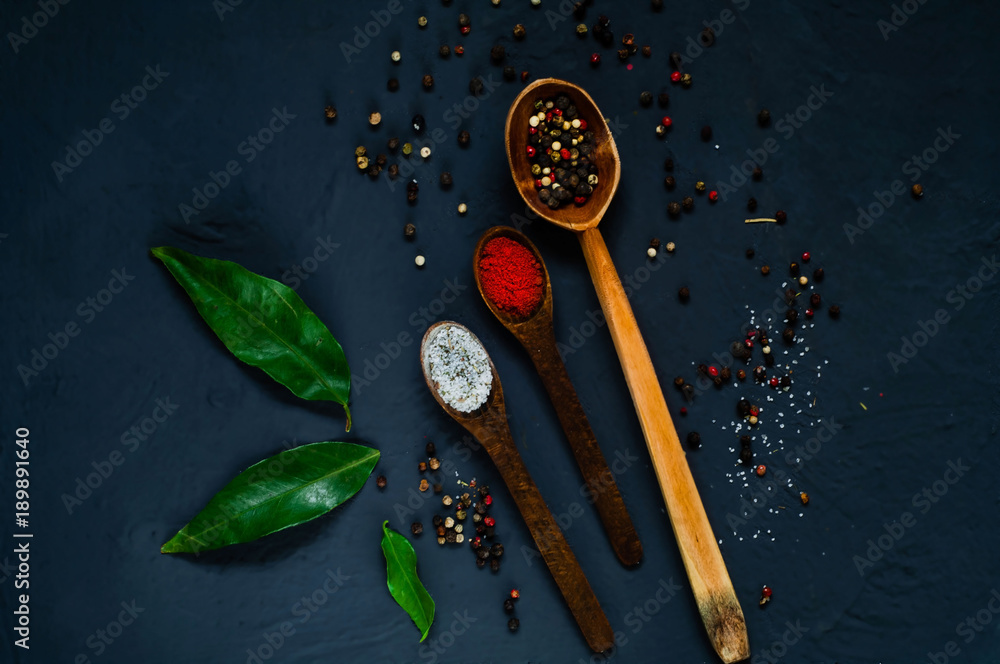 Wooden spoons and ingredients on a dark background. Concept of spicy food or cooking, top view, empty space for text Wooden spoons and ingredients on a dark background. Concept of spicy food or cooking, top view, empty space for text
