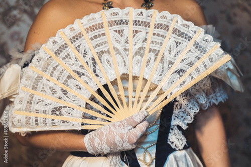 female hands keep a lacy fan in openwork gloves