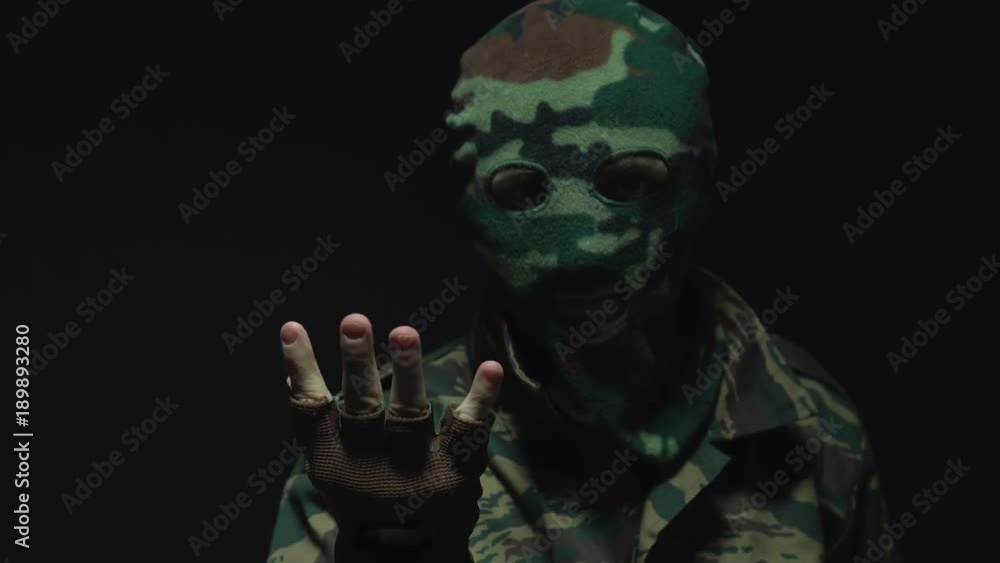 Portrait of soldier in camouflage and a military mask inviting for someone or something. Portrait of soldier in camouflage and a military mask inviting for someone or something.