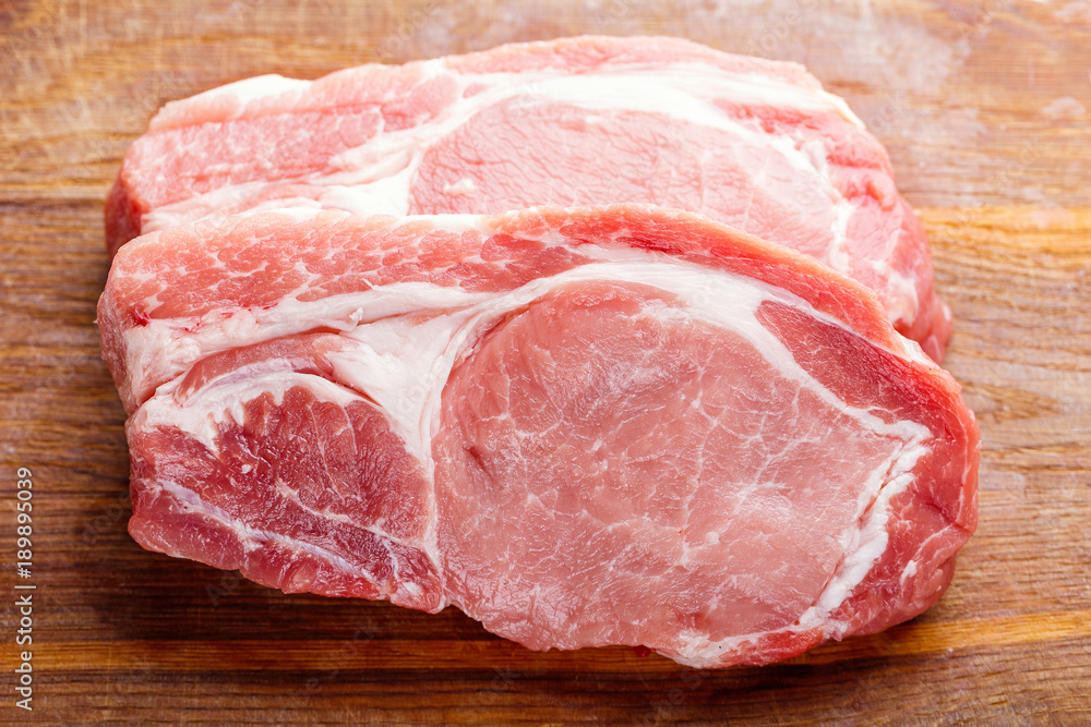 Raw pork natural cutlets on a wooden cutting board top view Raw pork natural cutlets on a wooden cutting board top view