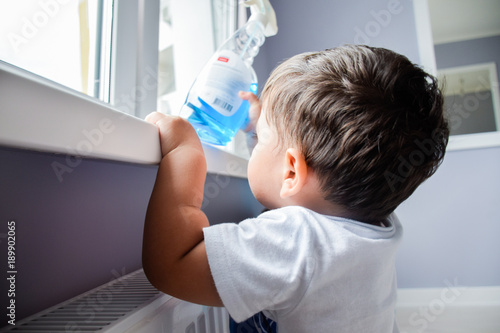 Billede på lærred Little latin boy reaching a toxic cleaning product.