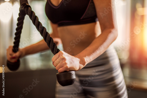 Woman doing rope pushdowns for triceps at the gym closeup photo