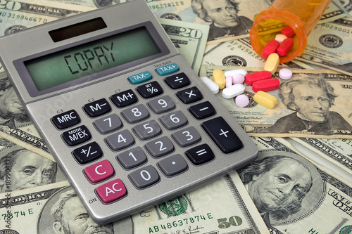 copay text on calculator with money and prescription pills in bottle photo