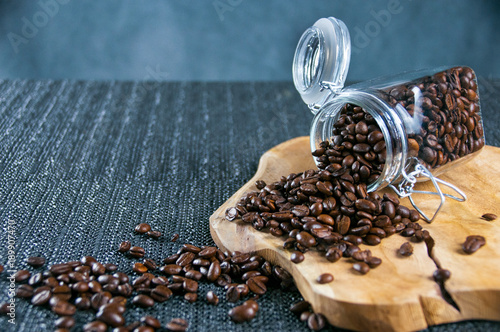 Coffee beans in a crystal jar on a brown wooden backgroundand old gilt metal coffee cup photo