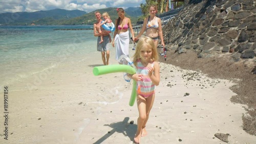 Happy caucasian family with kids walking on white sand beach photo