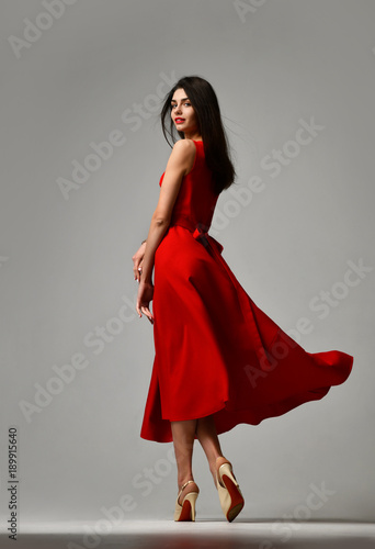 Billede på lærred Pretty brunette woman in formal red dress stiletto heels shoes